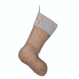 A beige burlap Christmas stocking with blue stripes and two hand-sewn wooden buttons, hanging from a braided jute loop.