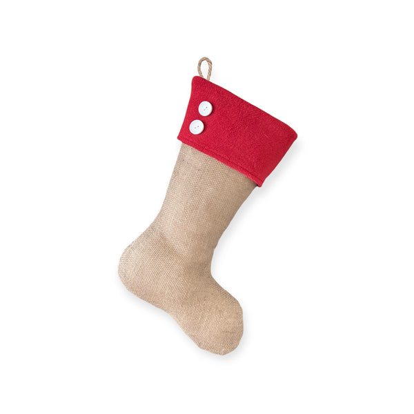 A handmade, natural burlap Christmas stocking, with red fleece cuff and two  white buttons, hanging from a braided jute loop. Made by BurlapBabe.