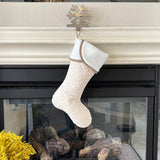 BurlapBabe handmade quilted Christmas stocking in cream with a white cuff hanging on a fireplace mantle