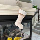 BurlapBabe quilted Christmas stocking in cream fabric with a burlap trim hanging on a fireplace mantle