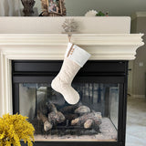 BurlapBabe quilted Christmas stocking in cream fabric with wood buttons hanging from a fireplace mantel