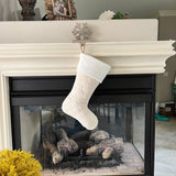 BurlapBabe quilted cream stocking with a soft white fleece cuff hanging from a fireplace mantel.