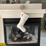 BurlapBabe quilted ivory cotton Christmas stocking with a white fleece cuff and two red wood buttons hanging on a mantel