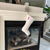 BurlapBabe quilted ivory cotton Christmas stocking with a white fleece cuff and two red wood buttons hanging on mantel