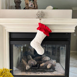 BurlapBabe quilted white Christmas stocking with a red ruffled cotton cuff hanging from a fireplace mantel