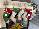 BurlapBabe red and green Christmas stocking style A with striped foot and jute loop hanging on a fireplace mantel
