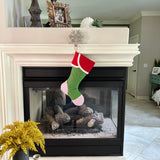 BurlapBabe red and green Christmas stocking with striped toe hanging from a snowflake hook on a fireplace mantel