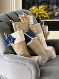 BurlapBabe set of five rustic Christmas stockings featuring burlap, blue ticking fabric, and decorative buttons.