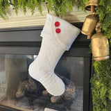 BurlapBabe white quilted Christmas stocking with fleece cuff and two red wooden buttons hanging by a fireplace