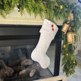 BurlapBabe white quilted Christmas stocking with fleece cuff and two red wooden buttons hanging by a fireplace